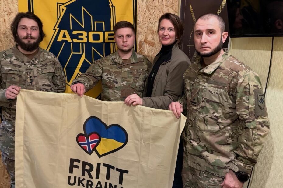 To soldater og Natalia Golis foran banner og bak flagg.