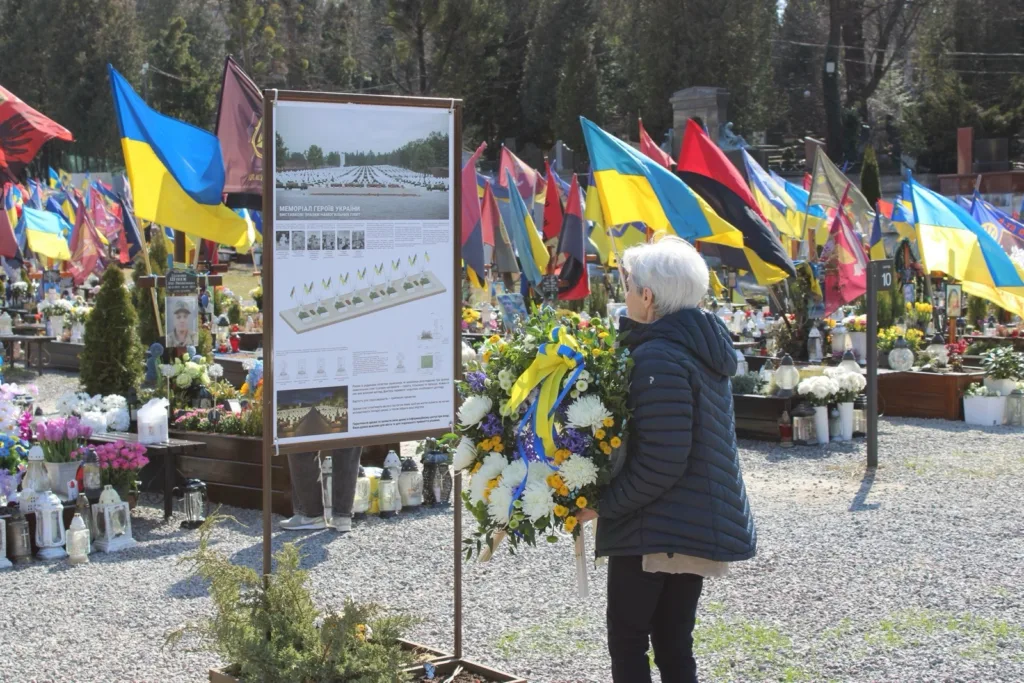 Anneliese på æreskirkegården i Lviv med krans. Graver og flagg i bakgrunnen