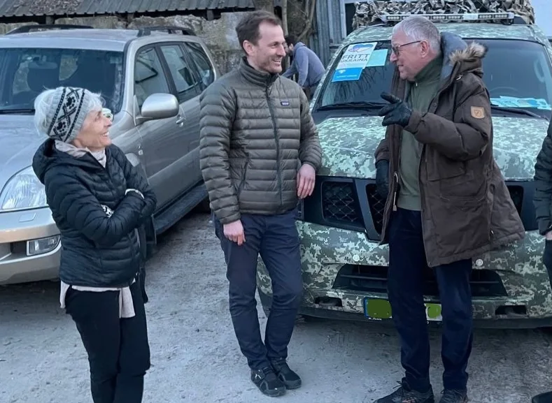 Tre personer står foran flere bilder og snakker sammen